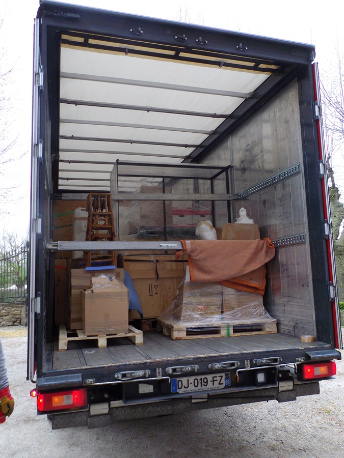 le camion est rempli d'objets divers ( malles en bois, tableaux )